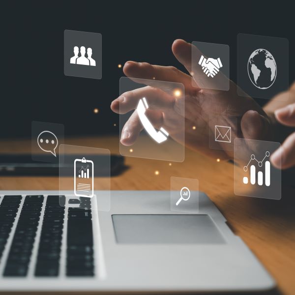 person typing on laptop with icons such as phone people, world, two hands shaking, graphs coming out of screen.
